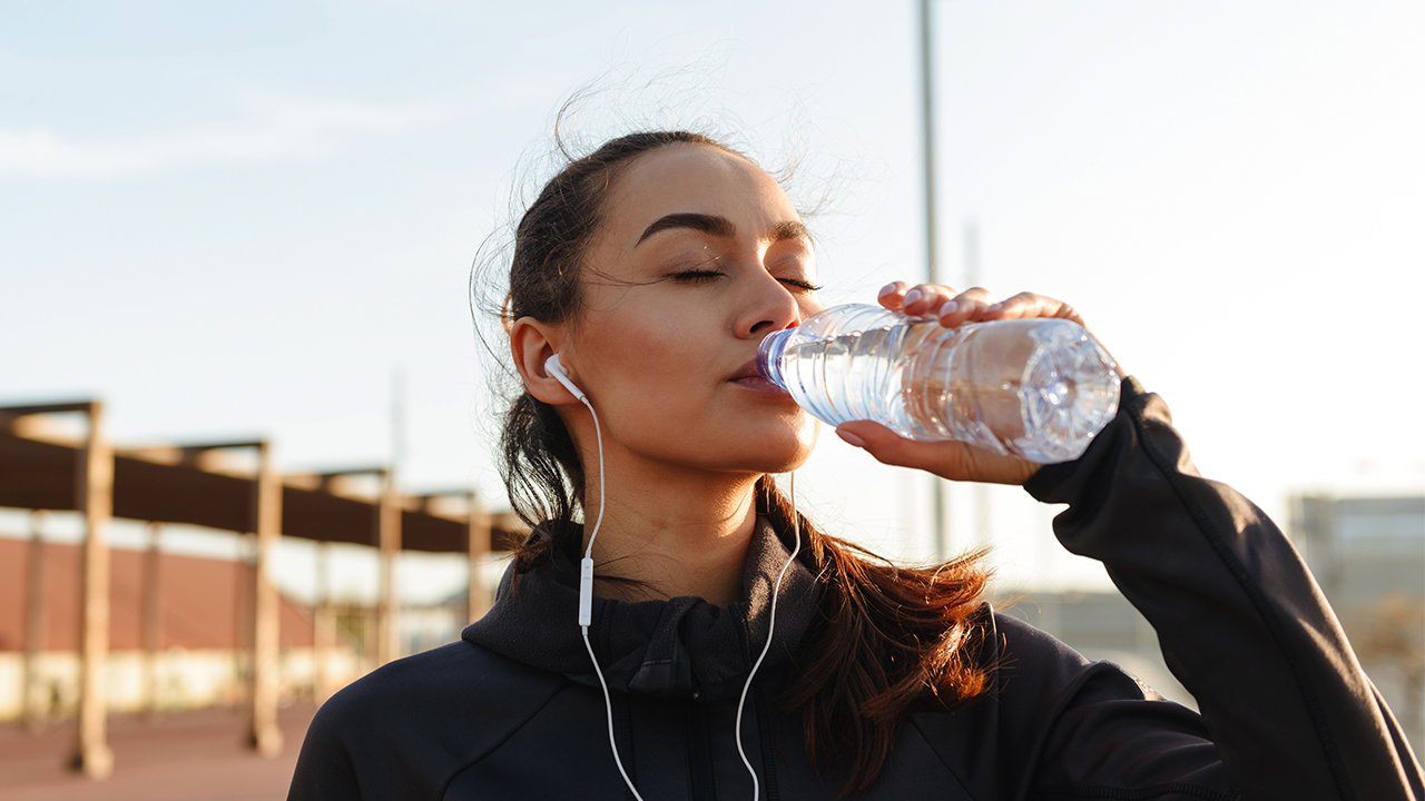 A woman pauses from exercising to drink water