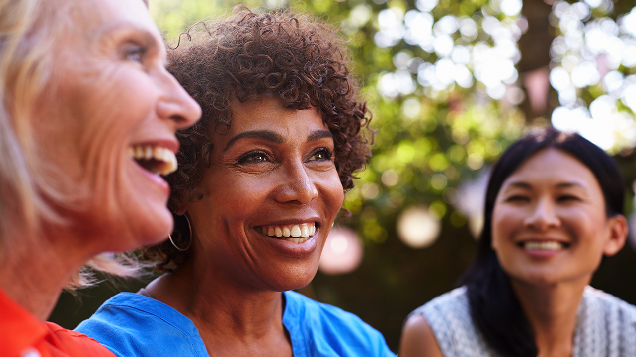 Three women sit together smiling