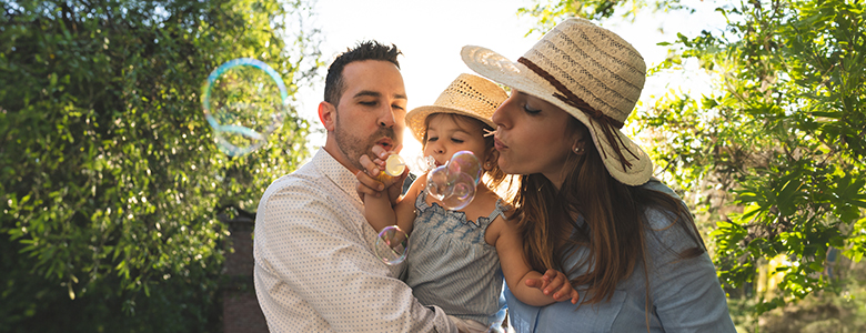 A man and woman blow bubbles with a toddler