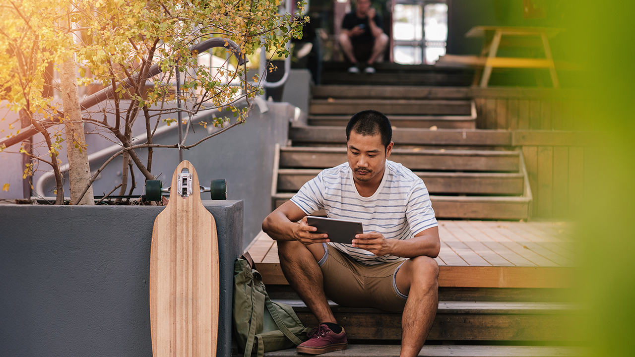 A man sits and reads from a tablet