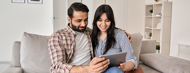 A young couple sits together reading from a tablet